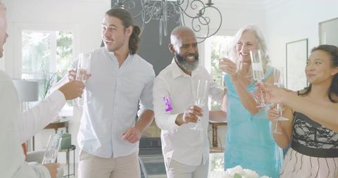 Friends Toasting Champagne and Celebrating at Elegant Home Gathering Under Chandelier