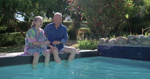 Senior couple sitting by pool chatting and dipping feet with animated health tips overlay