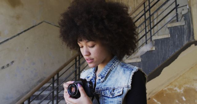 African american woman taking pictures with digital camera while standing near stairs. concept of gen z gender expression identity and diversity.
