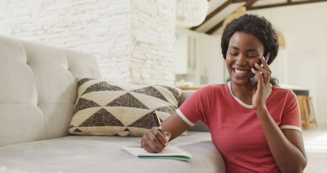 Woman Talking on Phone While Taking Notes in Bright Living Room - Download Free Stock Images Pikwizard.com