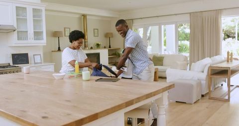 African american parents helping child pack backpack for school in bright kitchen