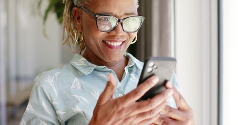Senior woman enjoying using smartphone indoors