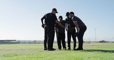 Baseball Team Huddling on Diamond Discussing Strategy Before Pitch Sunlit Grass Field Unity