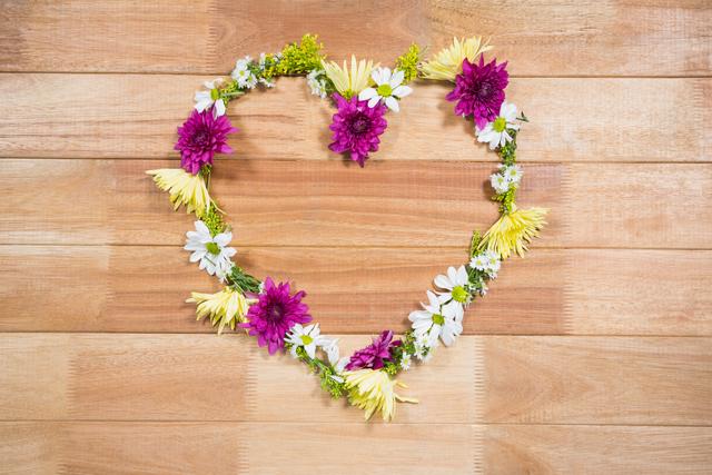 Tropical flower garland arranged in heart shape on wooden board, perfect for romantic themes, wedding invitations, Valentine's Day cards, and nature-inspired designs. Ideal for use in blogs, social media posts, and decorative projects.
