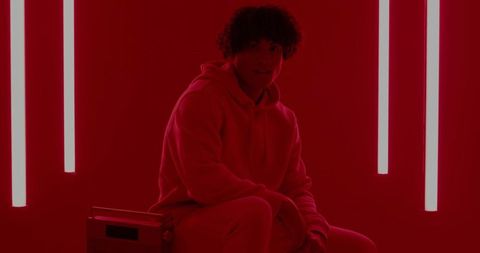 Person Wearing Hoodie in Red Studio with Neon Light Tubes