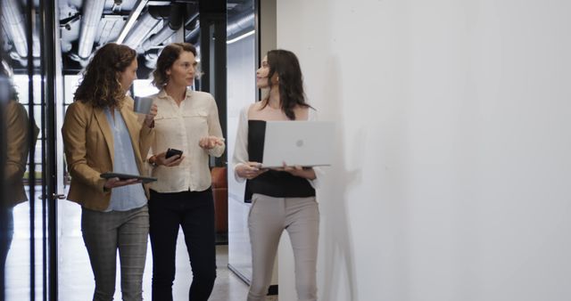 Businesswomen Collaborating and Discussing Work While Walking in Office - Download Free Stock Images Pikwizard.com