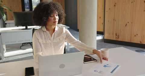 Professional woman reaching for report at workspace desk