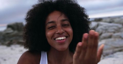 Joyful woman blowing kiss on beach with ocean background