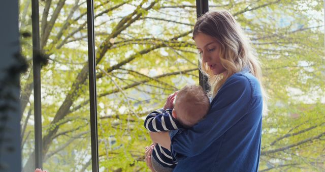 Young Mother Cradling Baby by Window in Daylight - Download Free Stock Images Pikwizard.com