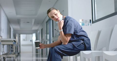 Exhausted nurse taking break in hospital corridor