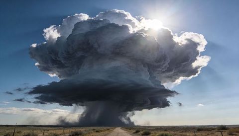Massive cumulonimbus thunderhead over arid plain with dramatic rain shaft and dust plume