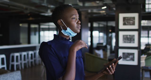 Thoughtful Woman with Facemask Holding Phone in Modern Office - Download Free Stock Images Pikwizard.com