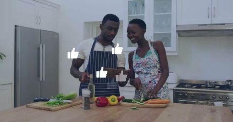 Couple following tablet recipe chopping fresh vegetables on kitchen island smiling