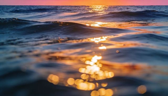 Golden sunset reflection on ocean surface with bokeh sparkle, rolling waves and warm horizon