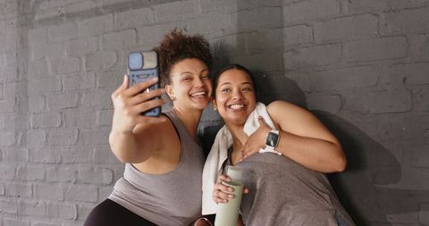 Smiling african american friends taking gym selfie after workout in activewear