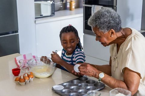 African american grandmother and granddaughter baking cupcakes together in modern kitchen