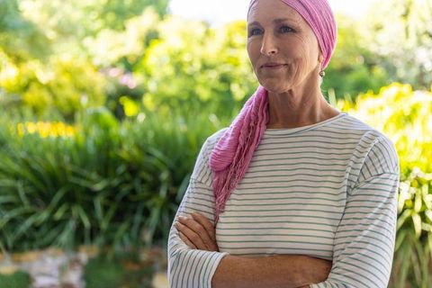 Senior woman with pink headscarf in lush garden