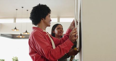 Diverse couple collaborating on home decor with spirit level