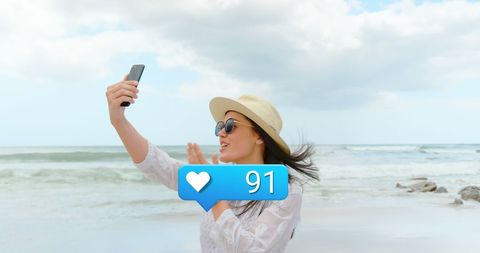 Woman Enjoying Beach Vacation Capturing Moment on Smartphone