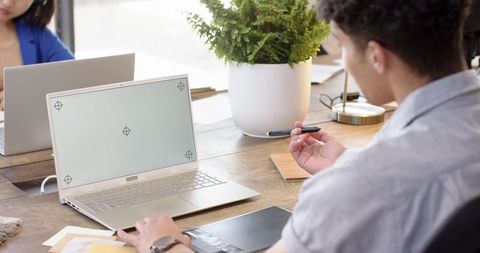 Young professionals collaborating over laptop at communal desk in modern coworking space