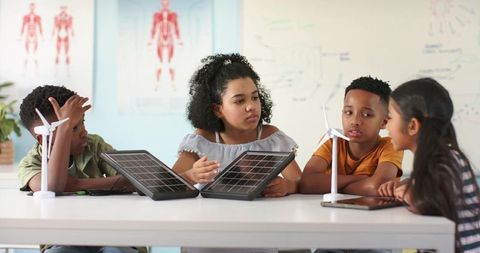 African american students collaborating on solar and wind energy project in classroom