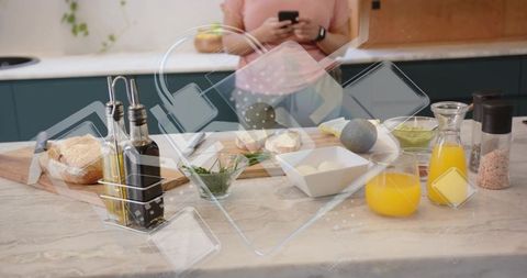 Young woman preparing healthy breakfast on marble kitchen island while checking smartphone