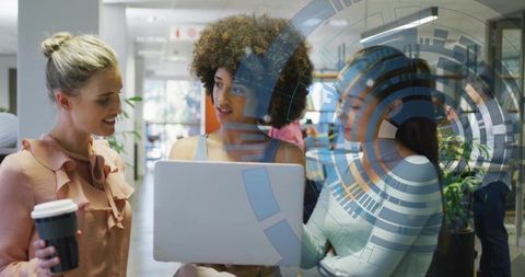 Three Women Collaborating Over Laptop in Modern Office Embracing Digital Innovation