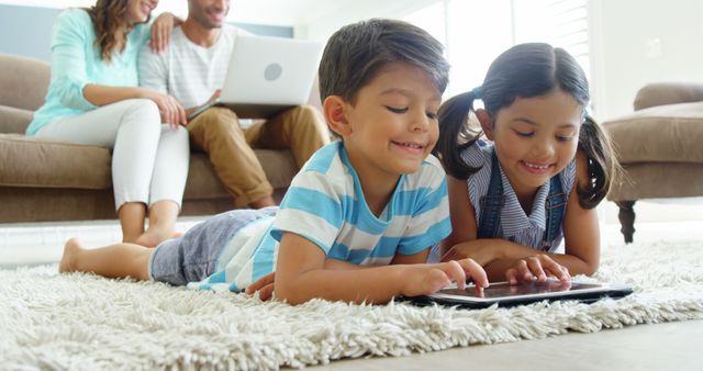 Happy Siblings Playing Tablet While Parents Relax on Sofa in Living Room - Download Free Stock Images Pikwizard.com