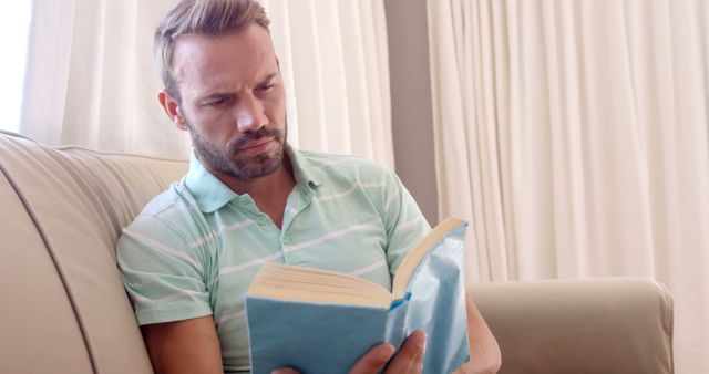 Man Reading Book on Sofa in Bright Room - Download Free Stock Images Pikwizard.com