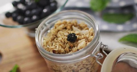 Glass Jar of Granola on Wooden Board with Fruits