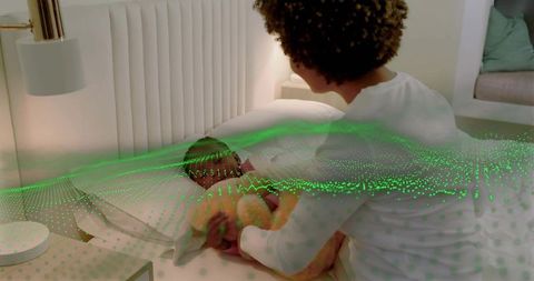 Mother tucking swaddled baby into bed while smart sleep sensor mapping nighttime comfort