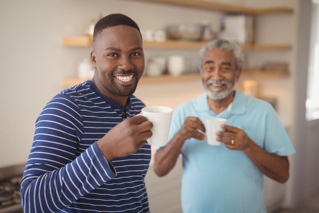Portrait of smiling father and son having cup of coffee in kitchen at home