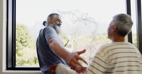 Mature couple reaching through window with wireframe heart overlay, mountain view