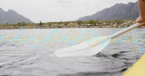 Paddle Dipping into Lake During Mountain Kayak Adventure
