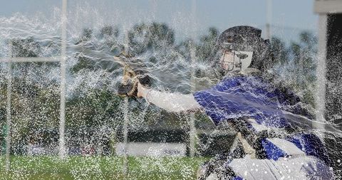 Leaning baseball catcher reaching for impressive catch on field