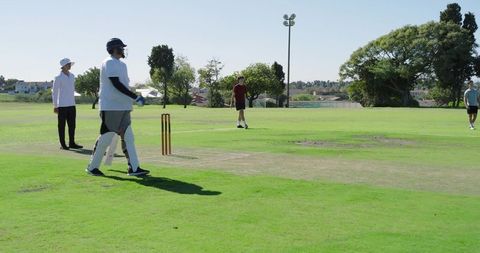 Batsman watching bowler delivering ball on sunny club cricket pitch