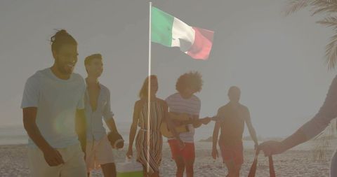 Young friends walking on sunset beach with italian flag and acoustic guitar celebration