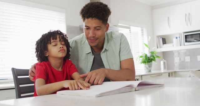 Father and young daughter reading together at kitchen table, signifying educational bond and quality family time. Perfect for themes related to parenting, education, family bonding, and modern home life.