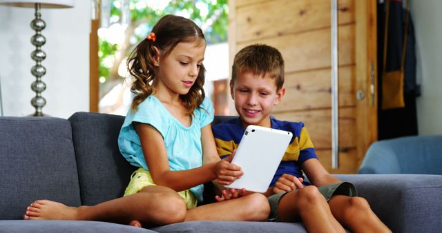 Happy Siblings Using Tablet on Sofa - Download Free Stock Images Pikwizard.com