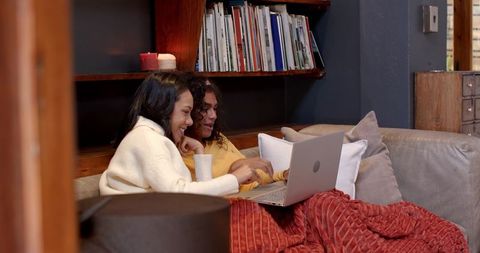 Relaxed Friends Bonding on Sofa Using Laptop at Home