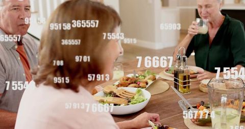 Older adults sharing healthy dinner around wooden table, laughing and dining under digital overlay