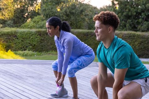 Diverse Pairs Doing Kettlebell Deadlifts on Wooden Deck Outdoors