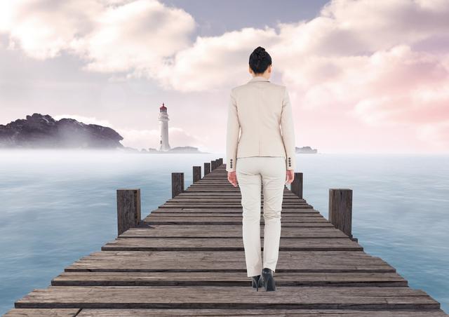 Businesswoman in a beige suit walking on a wooden pier towards the sea with a lighthouse in the distance. The scene is calm and serene with a misty atmosphere and soft clouds in the sky. Ideal for concepts of journey, determination, solitude, and professional life. Suitable for use in business presentations, motivational materials, and travel-related content.