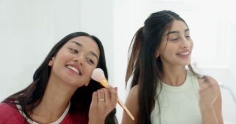 Diverse young women cheerfully applying makeup together