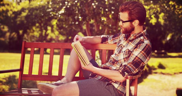 Man relaxing on bench reading book in sunny park - Download Free Stock Images Pikwizard.com