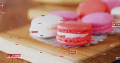 Pink and white macarons on wooden board with floating play subscribe like badges closeup