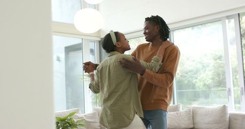 African American Couple Dancing Together in Sunlit Modern Living Room Embracing