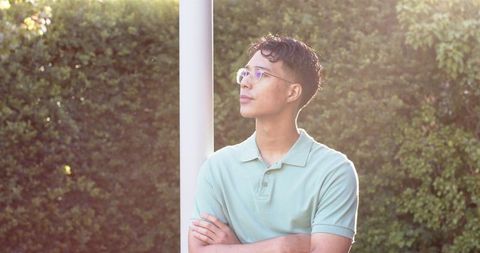 Thoughtful Young Man with Glasses in Sunlit Garden