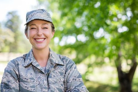 Smiling Female Soldier in Camouflage Uniform Outdoors