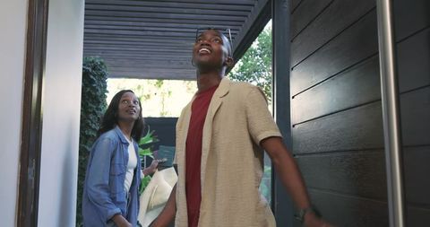 Young couple entering vibrant modern home under pergola